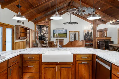 a kitchen with stainless steel appliances granite countertop a stove a refrigerator a sink a dining table and chairs with wooden floor