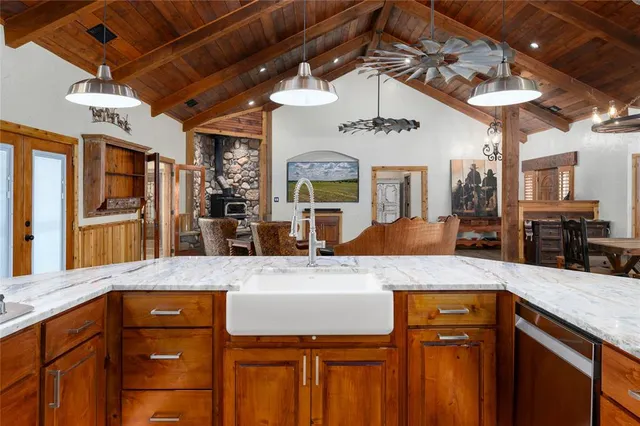 a kitchen with stainless steel appliances granite countertop a stove a refrigerator a sink a dining table and chairs with wooden floor