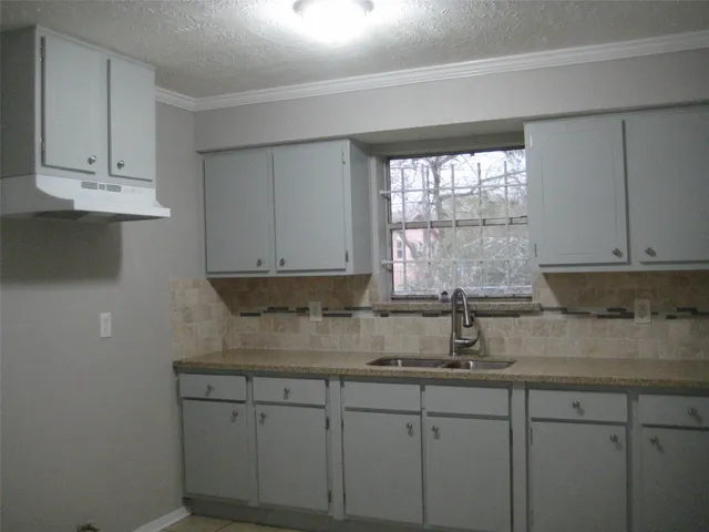 a kitchen with stainless steel appliances granite countertop white cabinets sink and window