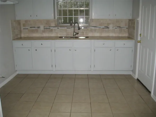 a kitchen with granite countertop white cabinets and sink