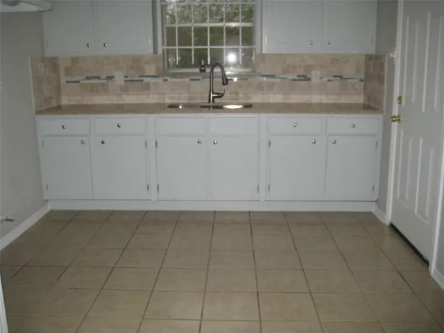 a kitchen with granite countertop white cabinets and sink