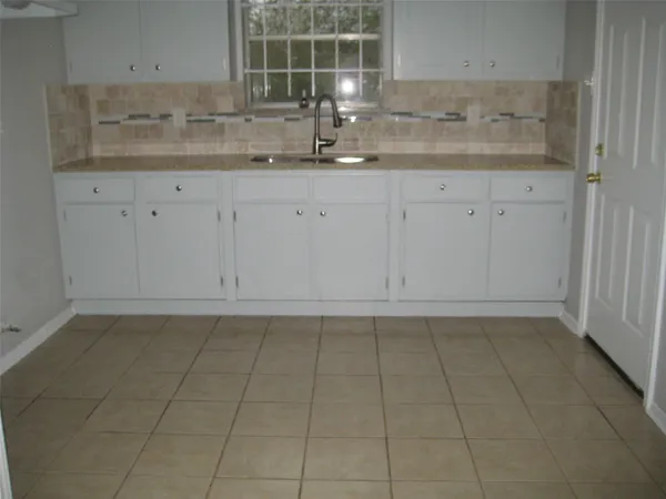 a kitchen with granite countertop white cabinets and sink
