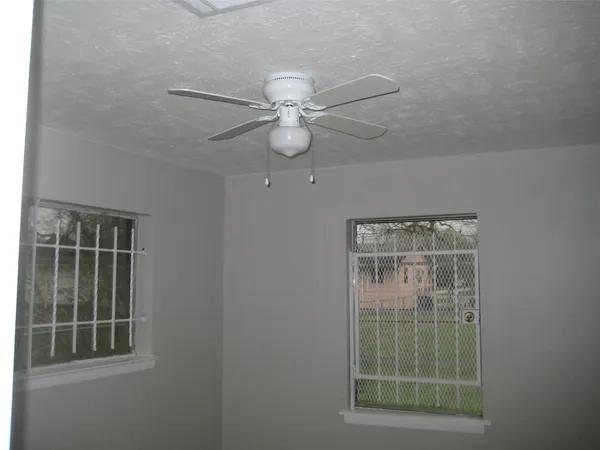 an empty room with windows and fan