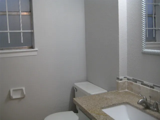 a bathroom with a granite countertop sink and a toilet