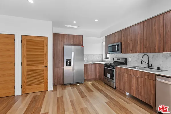 a kitchen with stainless steel appliances granite countertop a refrigerator stove top oven and sink