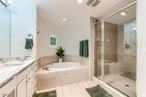 a bathroom with a tub shower sink and mirror