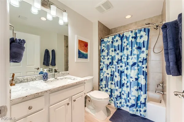 a bathroom with a granite countertop sink a toilet and a shower curtain