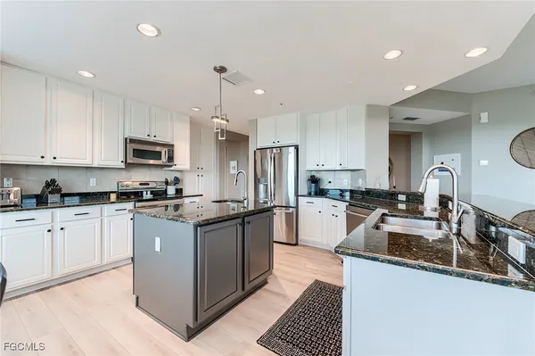a kitchen with granite countertop a sink and white cabinets