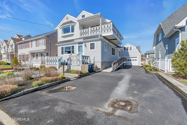 a view of a house with wooden deck furniture and a potted plant