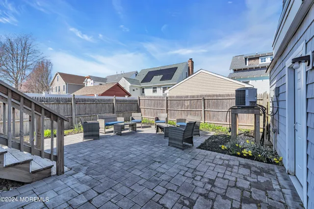 a view of a patio with couches table and chairs with wooden floor and fence