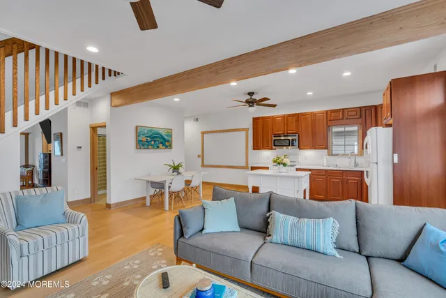 a living room with stainless steel appliances furniture a chandelier and a kitchen view