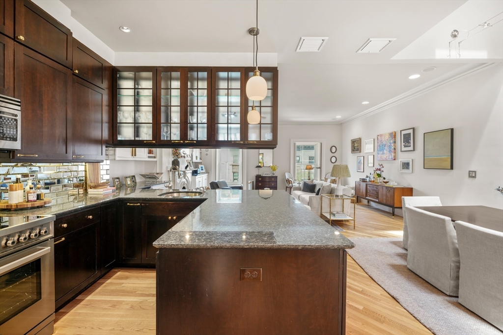 129 Beacon Street, Unit PH Boston, MA 02116 - Photo 8 of 40 a large kitchen with stainless steel appliances granite countertop a stove a sink dishwasher and a dining table with wooden floor