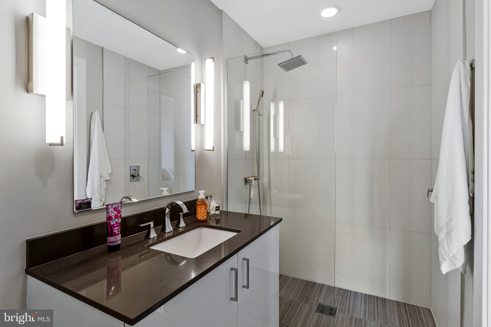 88 V Street Southwest, Unit 801 Washington, DC 20024 - Photo 31 of 58 a bathroom with a granite countertop sink a mirror and a shower