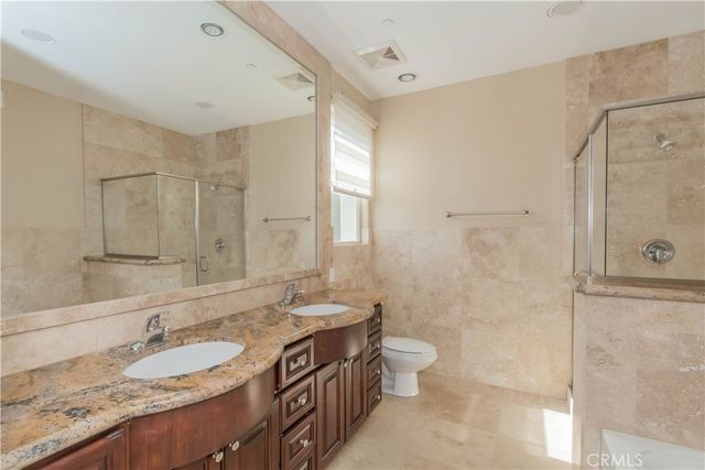 a bathroom with a granite countertop double vanity sink toilet and shower