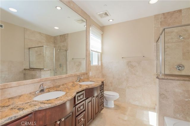 a bathroom with a granite countertop sink a toilet and shower