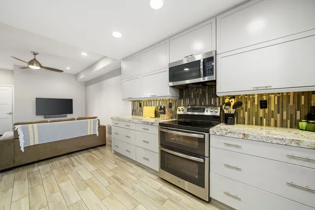 a kitchen with stainless steel appliances a dining table chairs and wooden floor