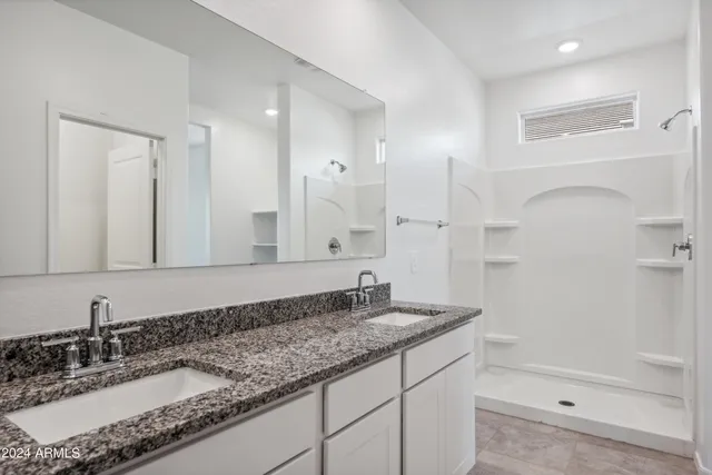 a bathroom with a granite countertop sink a mirror and shower