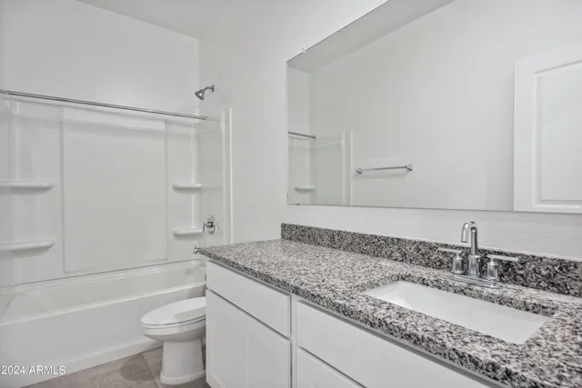a bathroom with a granite countertop sink a toilet and bathtub