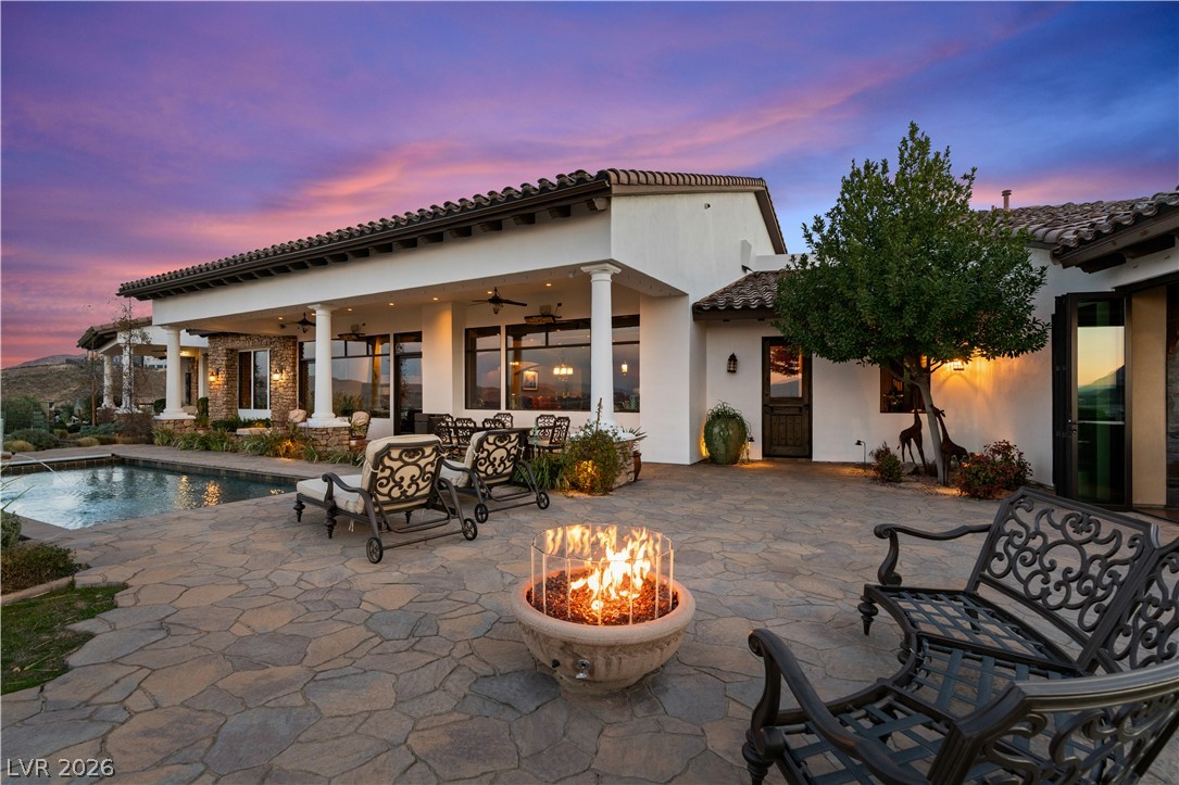 1123 Christian Road Henderson, NV 89002 - Photo 70 of 94 An inviting outdoor oasis features a refreshing pool, expansive patio, and fire pit, all beneath a colorful twilight sky.