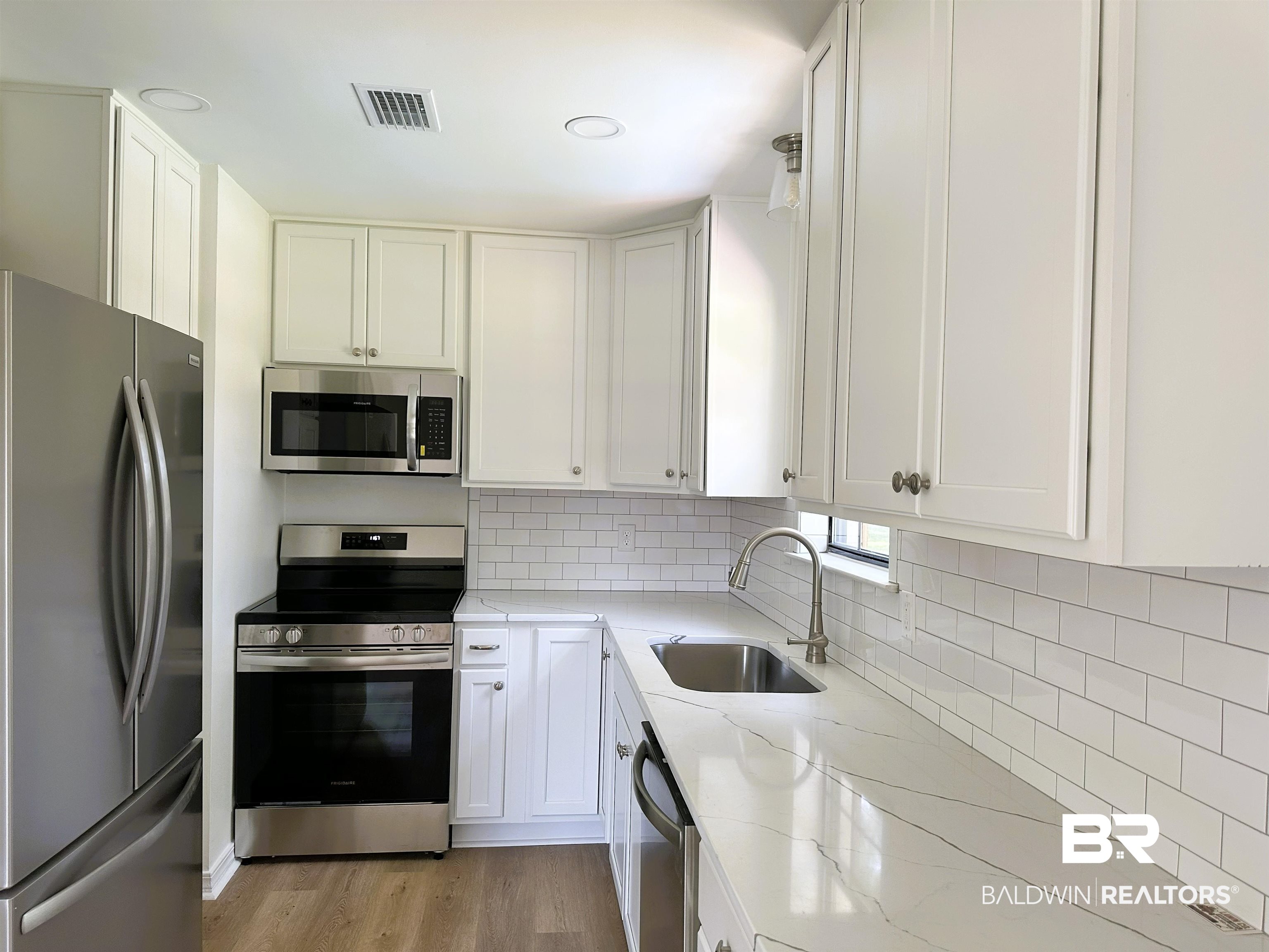 701 McRae Street Atmore, AL 36502 - Photo 3 of 11 Kitchen with stainless steel appliances, white cabinets, light stone counters, and light wood-style floors