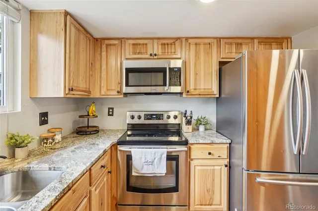 a kitchen with stainless steel appliances granite countertop a refrigerator and a stove top oven