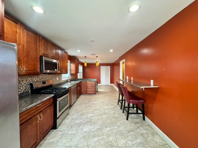 a kitchen with granite countertop a refrigerator stove top oven a sink and dishwasher