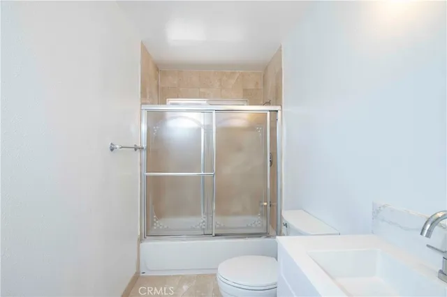 a bathroom with a granite countertop bathtub shower sink vanity and toilet