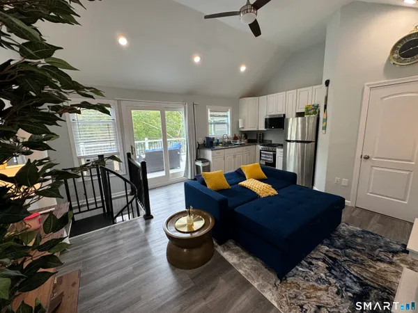 a living room with stainless steel appliances furniture a rug and a view of kitchen