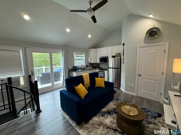 a living room with stainless steel appliances granite countertop furniture a rug a fireplace and a window