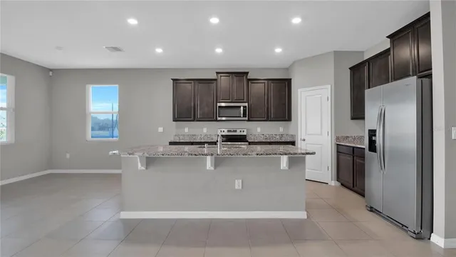 a large kitchen with stainless steel appliances granite countertop a refrigerator and a stove