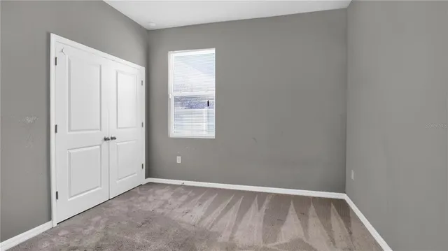 a view of an empty room with closet and a window