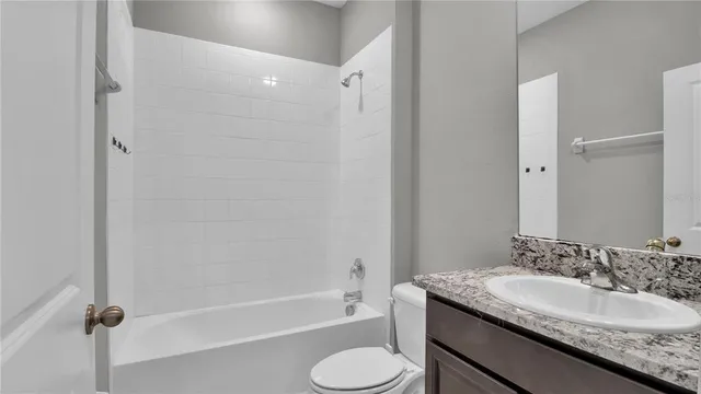 a bathroom with a granite countertop sink toilet tub and shower
