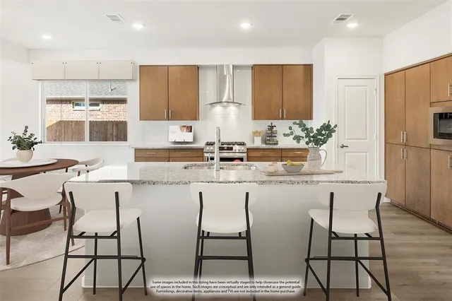 a kitchen with stainless steel appliances kitchen island granite countertop a dining table chairs and a refrigerator