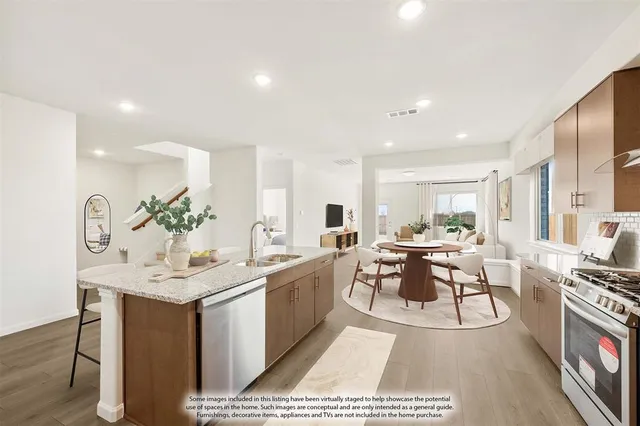 a living room with stainless steel appliances kitchen island granite countertop a sink and chairs