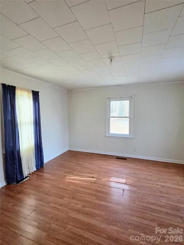 a view of a big room with wooden floor and windows