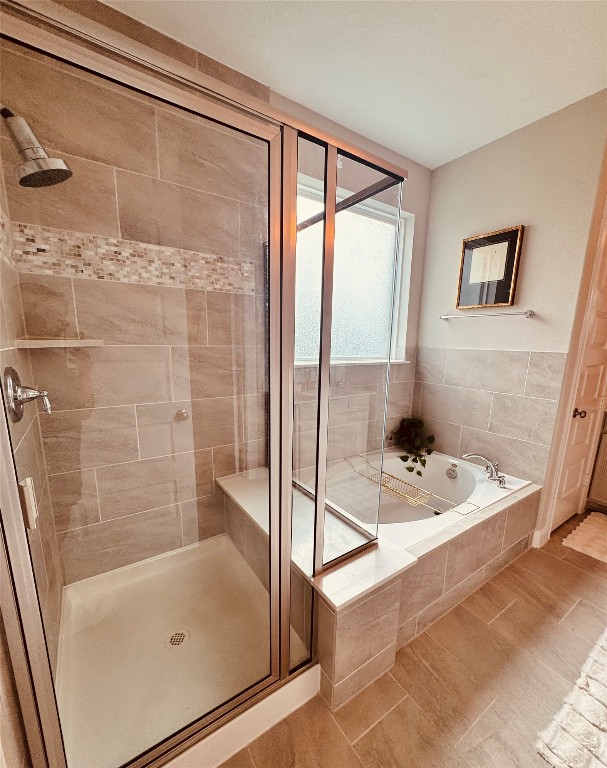 2023 Pine Ledge Road Pearland, TX 77089 - Photo 13 of 29 This bathroom features a modern glass-enclosed shower with stylish tile work and a separate soaking tub, offering a relaxing spa-like atmosphere.