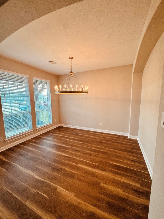 2023 Pine Ledge Road Pearland, TX 77089 - Photo 3 of 29 This room features elegant wood flooring, a modern chandelier, and ample natural light from large windows with blinds. The neutral walls and arched entryway create a warm and inviting atmosphere.