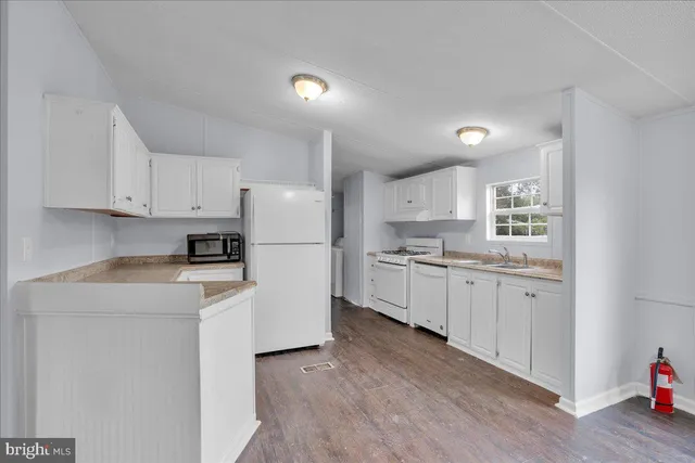 a kitchen with white cabinets white appliances and sink