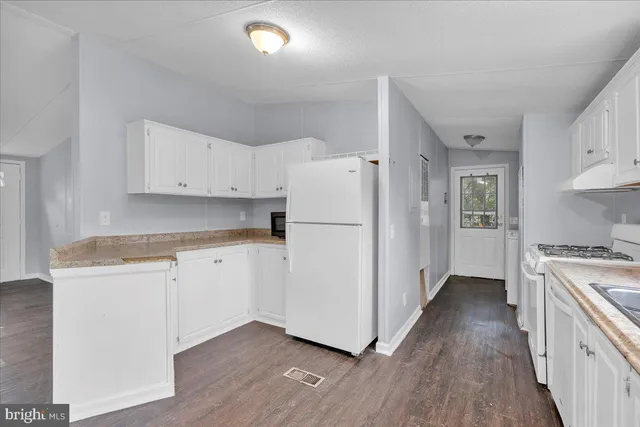 a kitchen with cabinets appliances wooden floor and a window