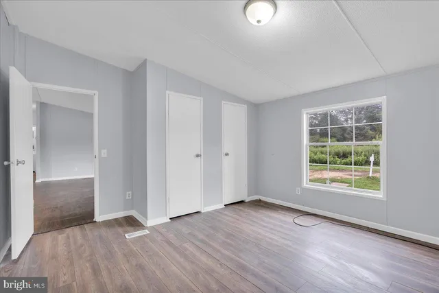 an empty room with wooden floor cabinet and windows