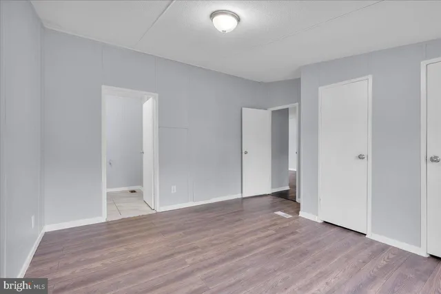 a view of an empty room with wooden floor and closet