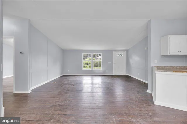 a view of an empty room with window and wooden floor