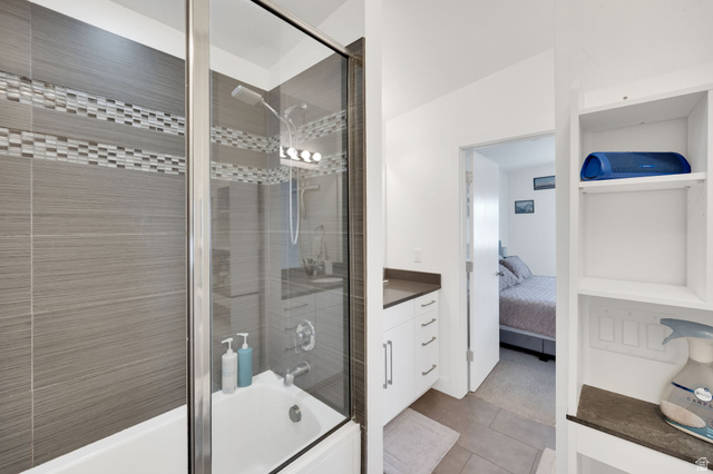 7713 Navarro View Court Midvale, UT 84047 - Photo 15 of 41 Bathroom featuring a tiled shower with glass enclosure, white bathtub, vanity with white cabinetry, and built-in shelving