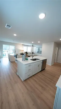 a large white kitchen with kitchen island a sink a stove a refrigerator with white cabinets and wooden floor