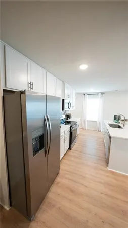 a kitchen with stainless steel appliances kitchen island granite countertop a refrigerator a sink a stove and white cabinets