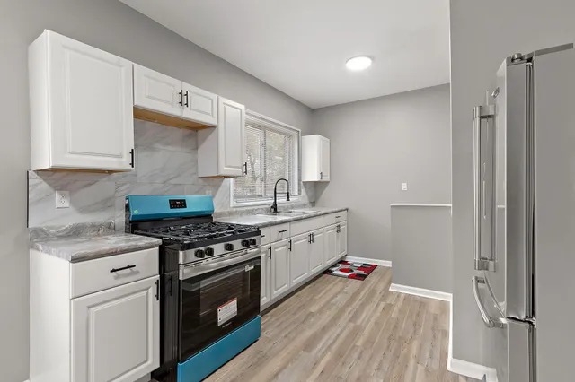 a kitchen with stainless steel appliances a stove and white cabinets