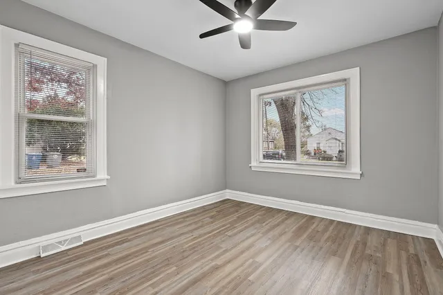 a view of a big room with wooden floor and windows