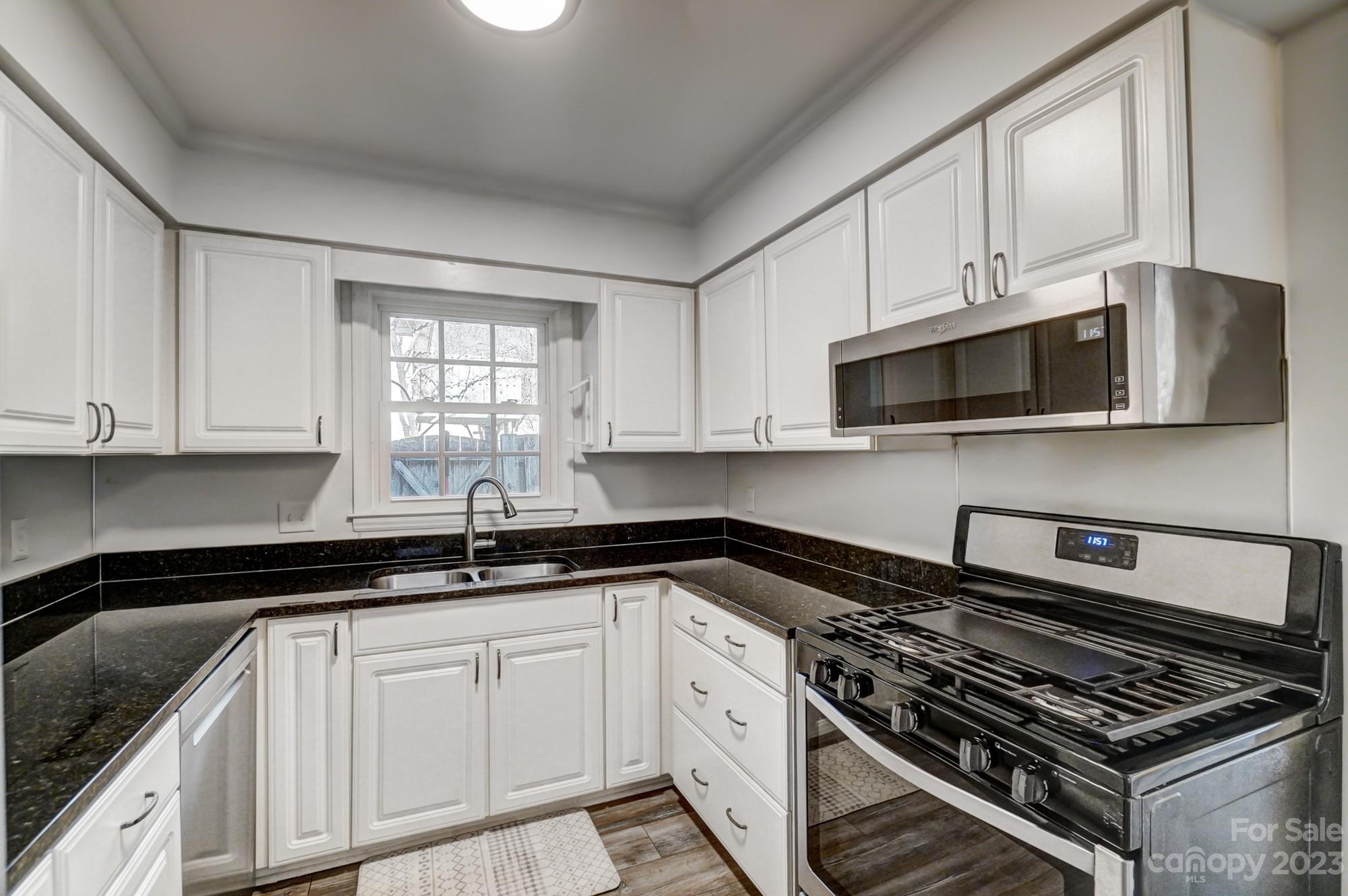 3500 Colony Road, Unit E Charlotte, NC 28211 - Photo 10 of 37 a kitchen with white cabinets a sink stove and microwave