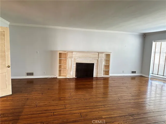 a view of empty room with wooden floor and fireplace