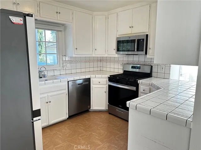 a kitchen with white cabinets and stainless steel appliances